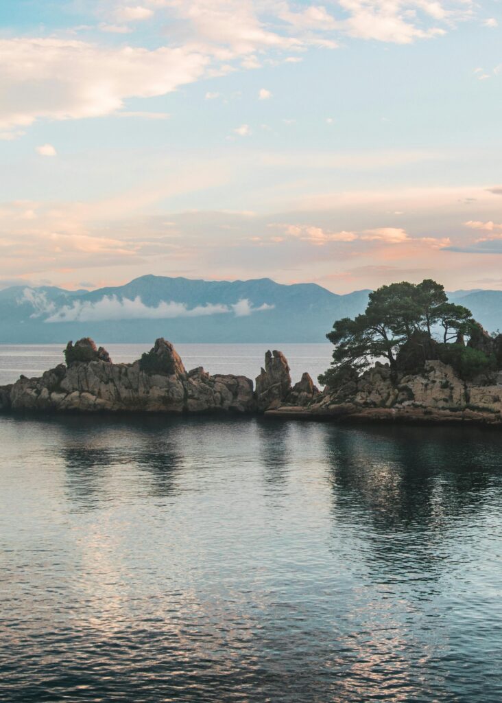 Serene Croatian coastline with rocky islands and soft twilight reflections.